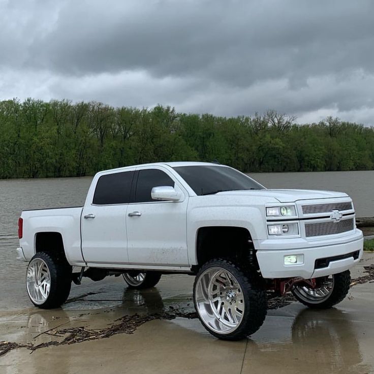 a white truck parked in front of a body of water