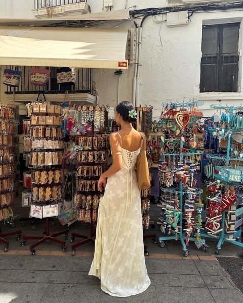 a woman in a white dress is looking at souvenirs