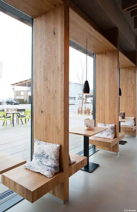 an empty restaurant with wooden benches and tables in front of large glass doors that look out onto the outdoors