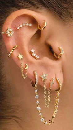 a woman wearing gold ear piercings with stars and moon designs