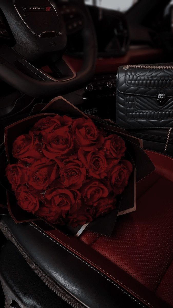 a bouquet of red roses sits in the center of a car's console area