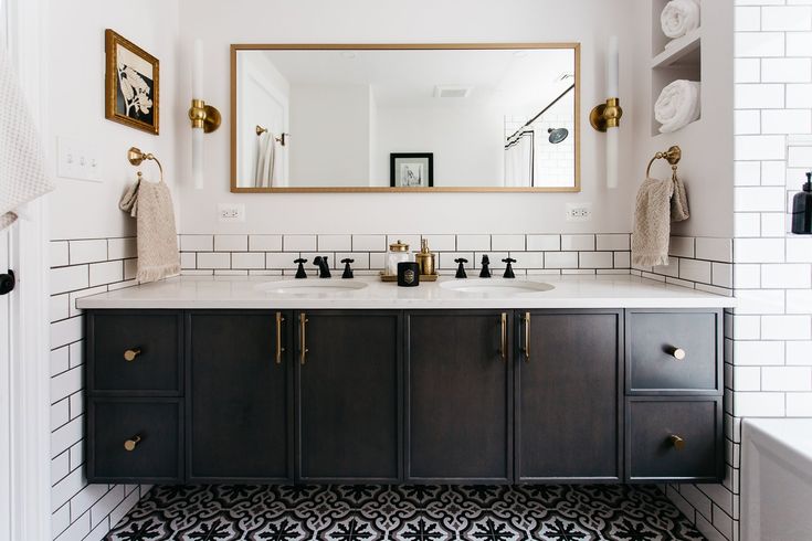 a bathroom with black and white tile, gold accents and mirrors on the wall above the sink