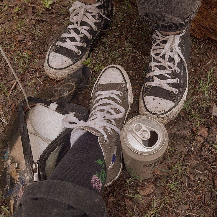 two people standing next to each other with their shoes on and one holding a can