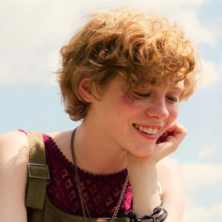 a young boy with red hair is talking on his cell phone while wearing a necklace