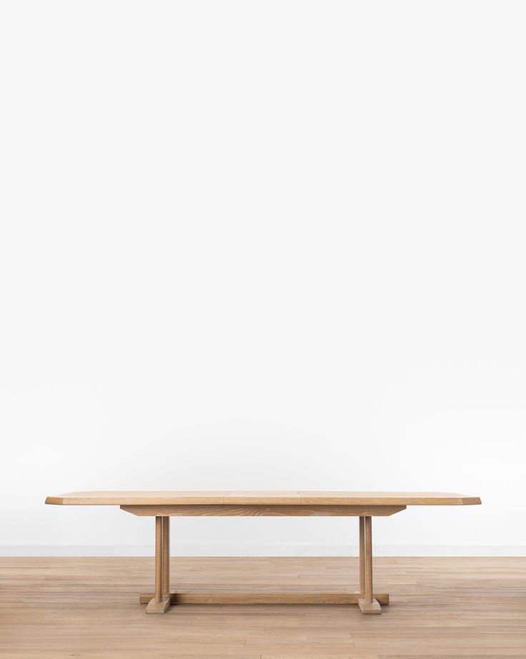 a wooden table sitting on top of a hard wood floor next to a white wall