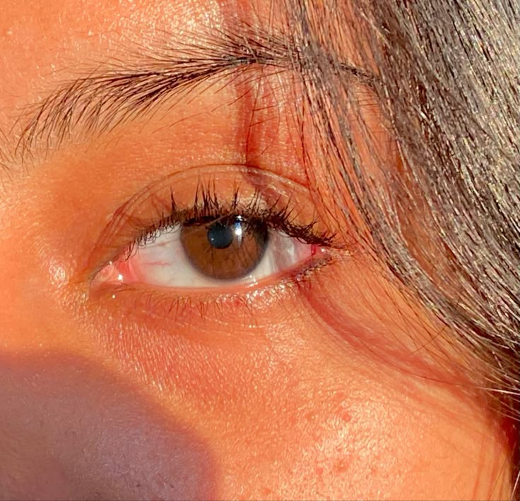 a woman's brown eyes are shown with long hair on the top of her head