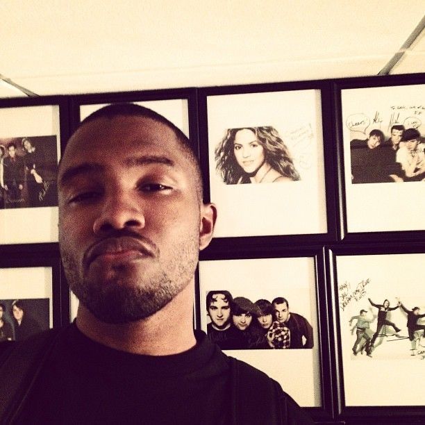 a man standing in front of a wall with many pictures on it and looking at the camera