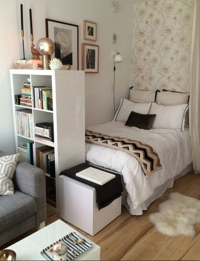 a bedroom with a bed, chair and bookshelf next to a couch in front of a window