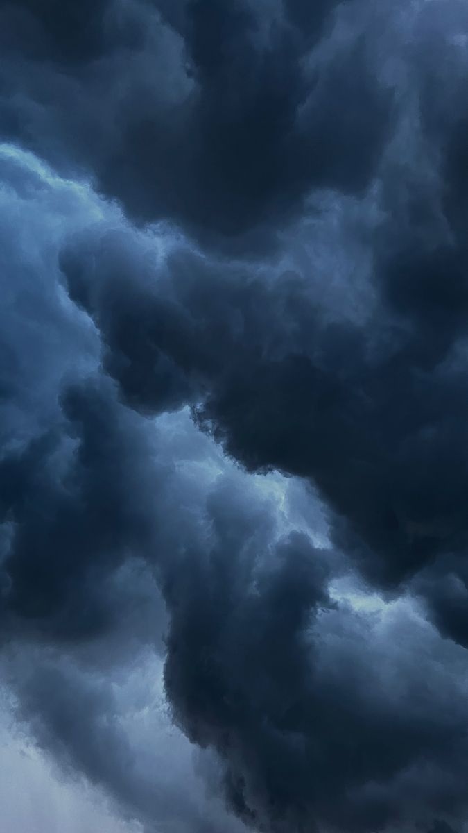 an airplane flying in the sky with dark clouds behind it and one plane on the ground