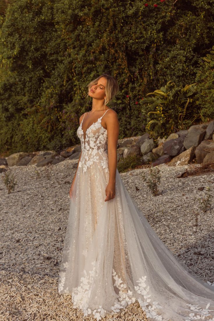 a woman in a wedding dress standing on gravel