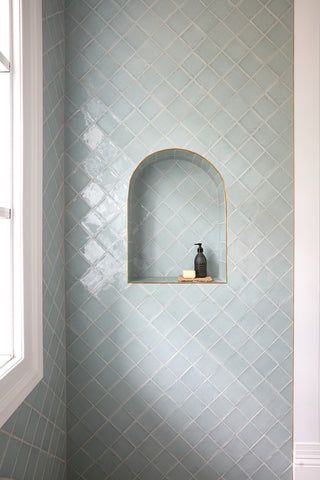 a white toilet sitting next to a window in a bathroom under a window sill