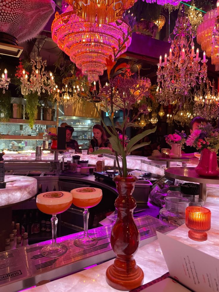 a bar with chandeliers hanging from the ceiling and wine glasses on the counter