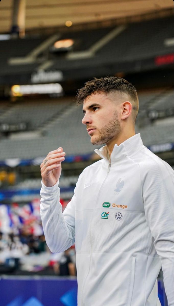 a man standing in front of a crowd wearing a white jacket and holding his hands together