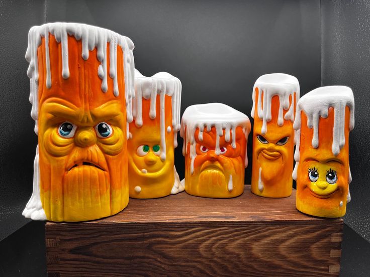 five orange and white candles with faces painted on them