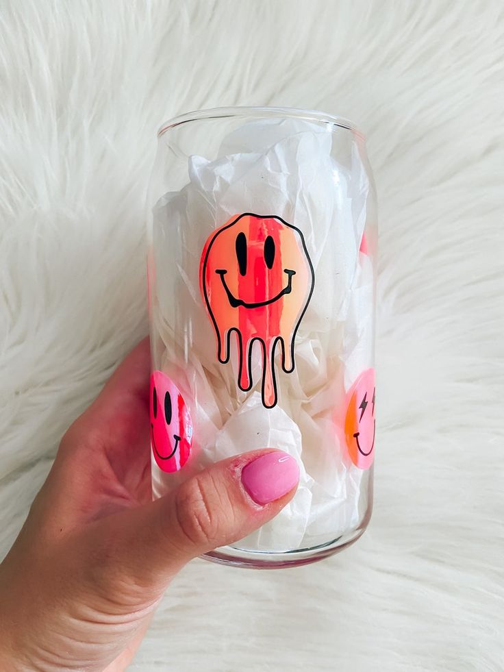 a hand holding a glass filled with marshmallows and an elephant drawn on it