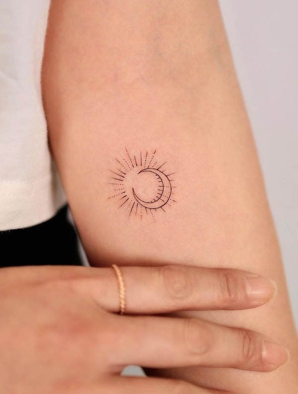 a woman's arm with a small sun tattoo on the left side of her arm