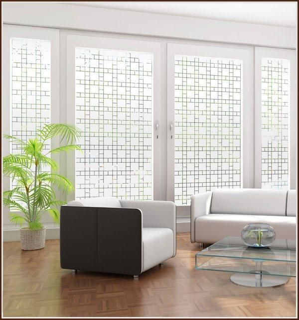 a living room filled with white furniture and large windows covered in glass coverings next to a potted plant