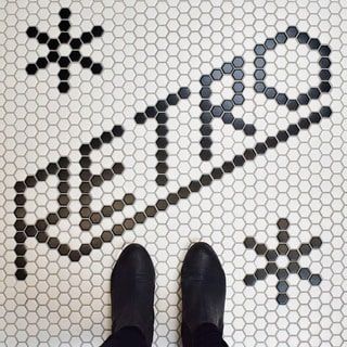 a person standing in front of a tiled floor with black and white designs on it