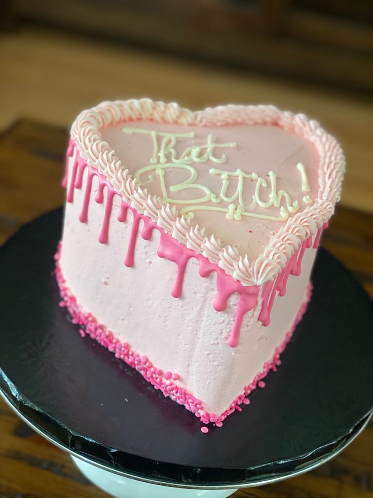 a heart shaped cake with pink icing on a black plate