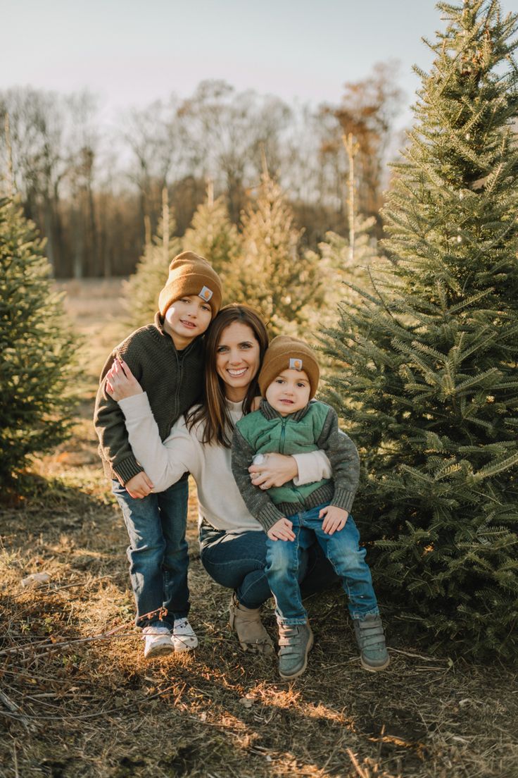 a mother and her two children standing in front of a christmas tree at the farm