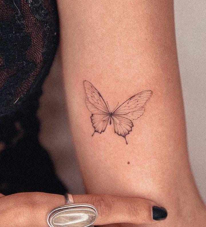 a woman's arm with a small butterfly tattoo on the left side of her wrist