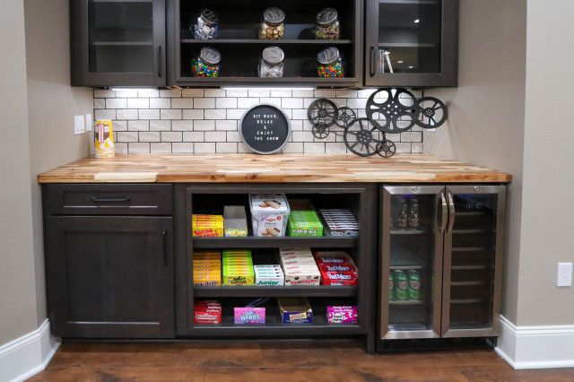 a kitchen with black cabinets and shelves filled with food, drinks and snacks on the counter