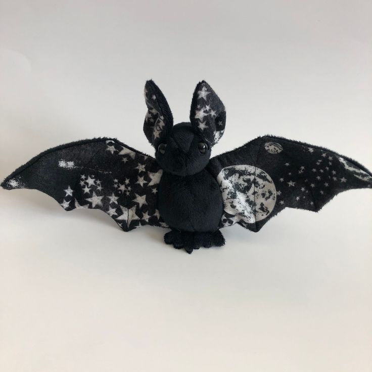 a stuffed animal bat with stars on it's back and wings, sitting in front of a white background