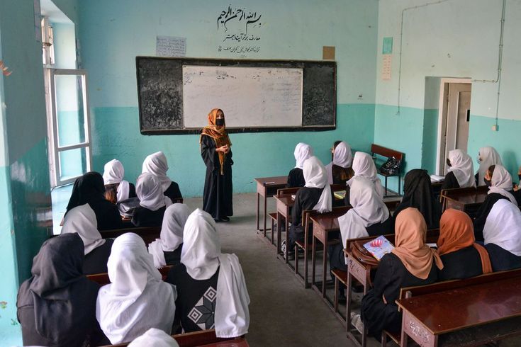 a group of women sitting at desks in front of a blackboard