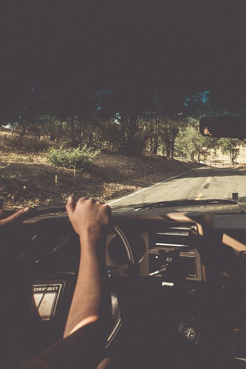 a person driving a car on a road at night with their hand on the steering wheel