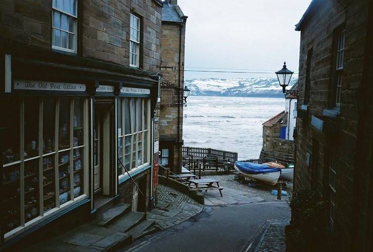 an alley way with buildings and boats on the water in the distance is a quote written by one person