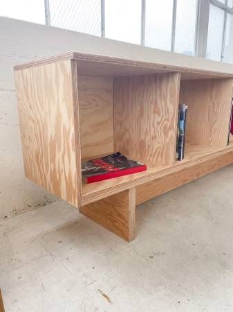 a wooden shelf with books on it in an empty room