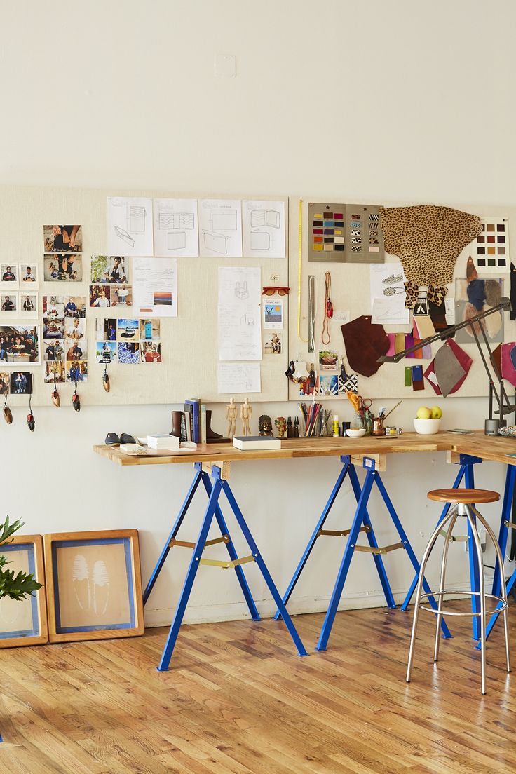 two stools sit in front of a desk with pictures on the wall behind it