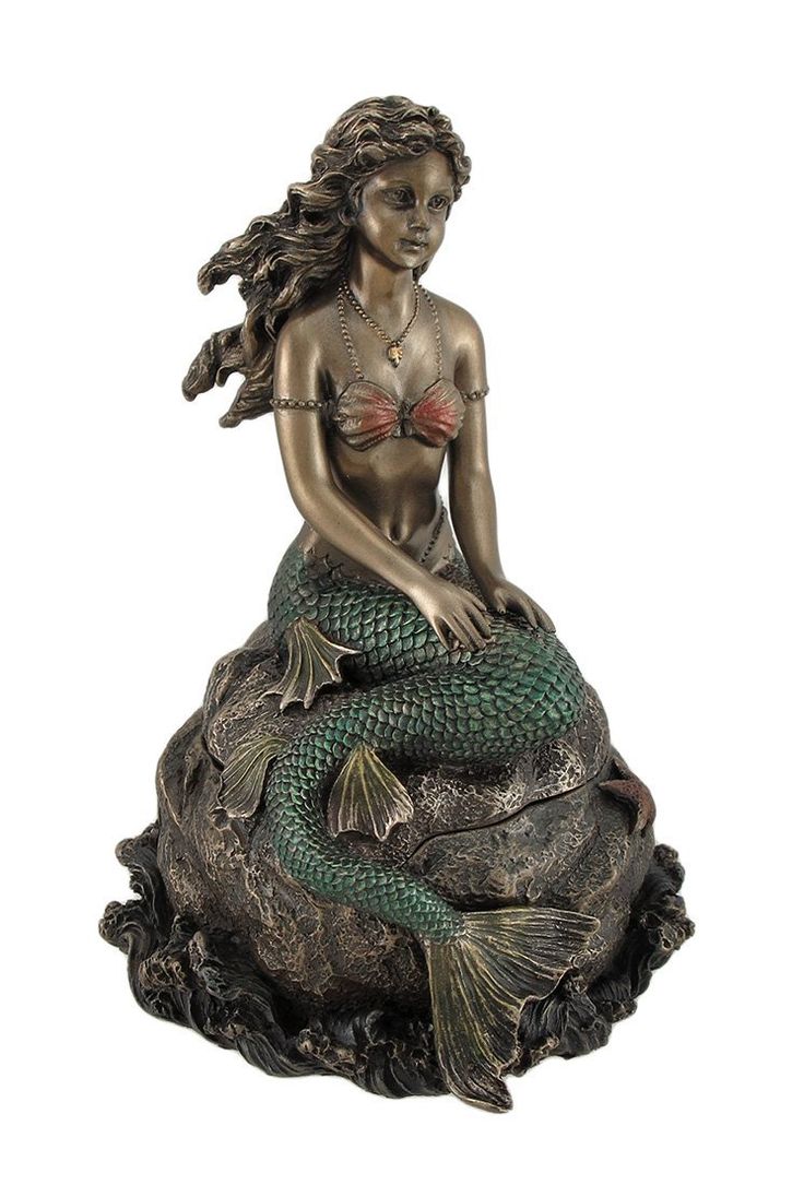 a statue of a mermaid sitting on top of a rock