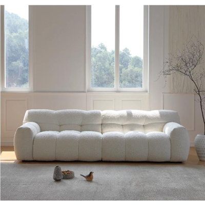 a white couch sitting on top of a rug next to a window