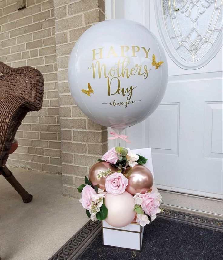 a large balloon sitting on top of a white box filled with pink and gold flowers