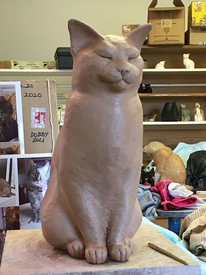 a cat statue sitting on top of a table next to a pile of clutter