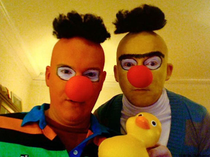 two people with clown noses and wigs are posing for a photo while holding a rubber duck