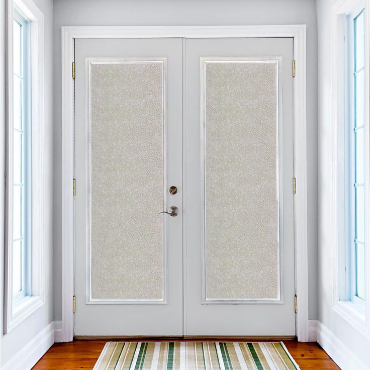 an empty room with two white doors and a rug on the floor next to it