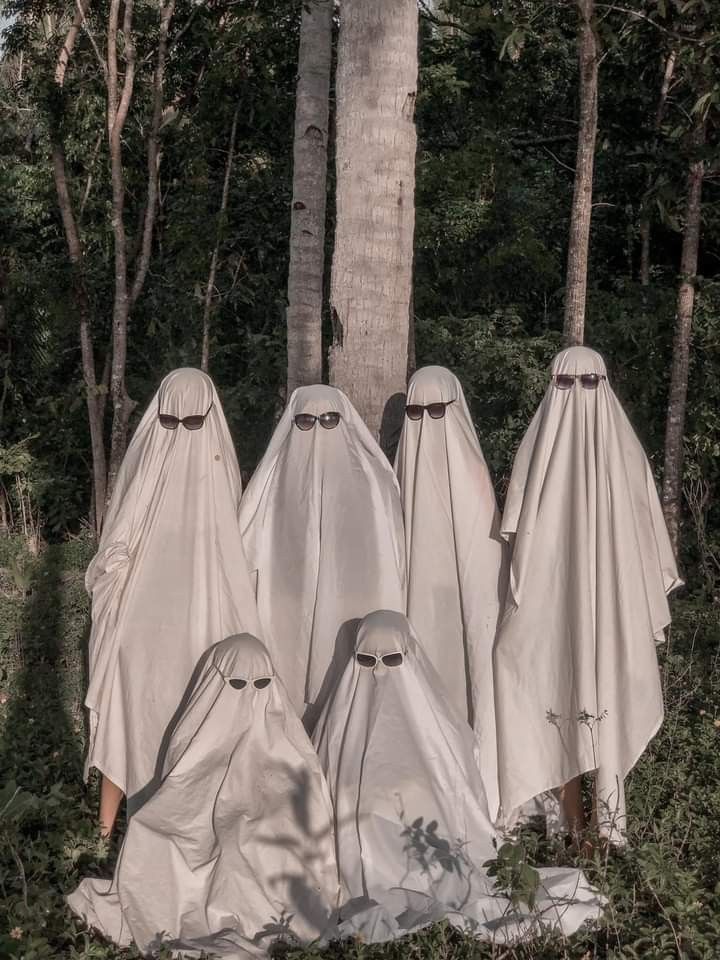 three white cloth covered ghost statues in the woods