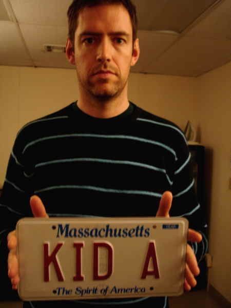 a man holding up a license plate that says, massachusetts gets kida the spirit of america