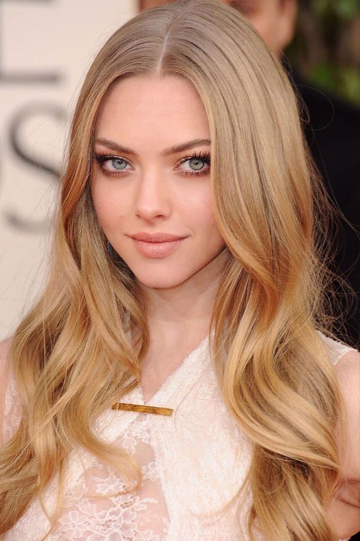 a woman with long blonde hair and blue eyes wearing a white dress at an event