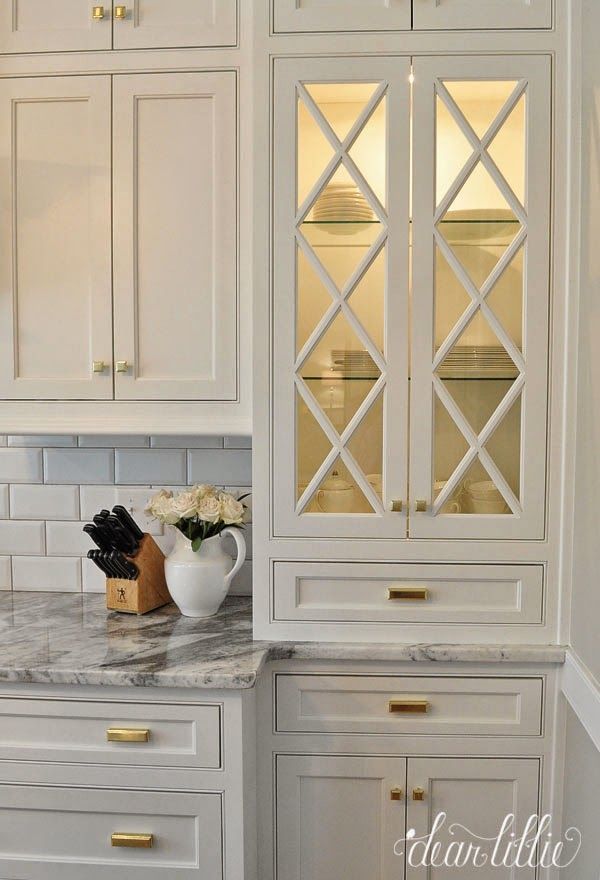 a kitchen with white cabinets and marble counter tops