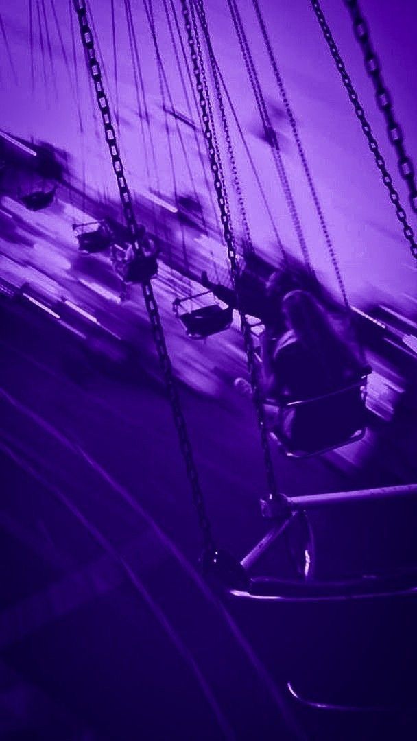 a purple photo of some swings in the dark