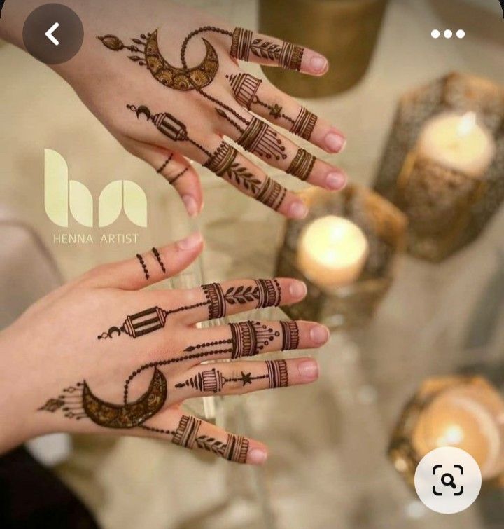 two hands with hendi designs on them and candles in the background, one is holding another hand