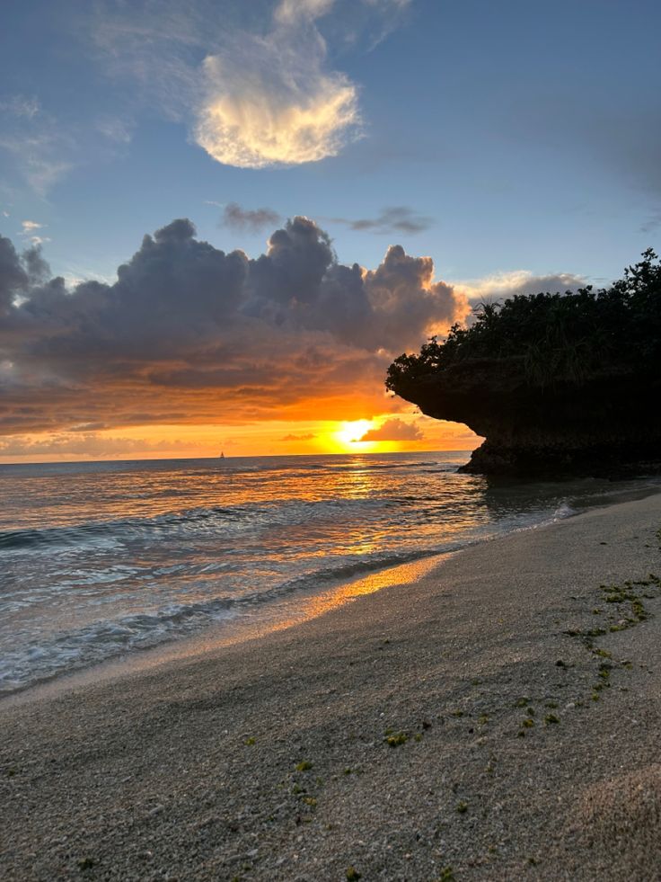 the sun is setting over the ocean with clouds in the sky and water on the beach