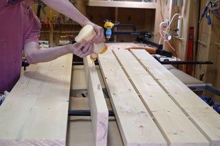 a man sanding wood on top of a wooden bench