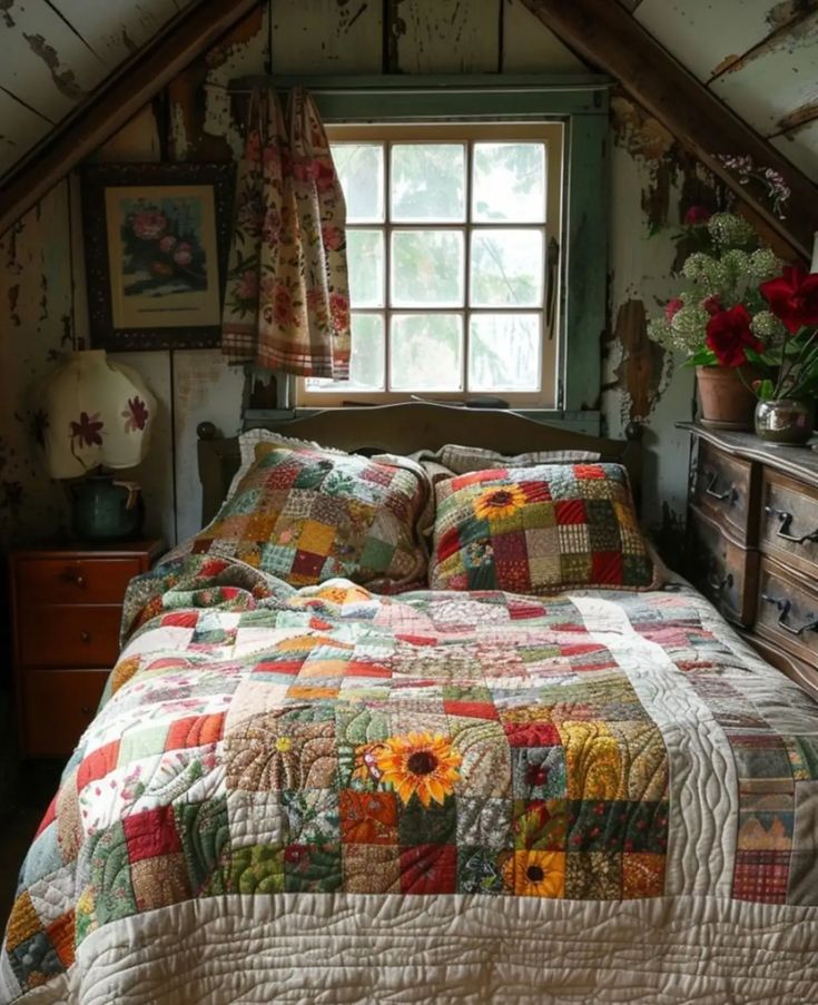 a bed in a room with a quilt on the cover and flowers hanging from the window