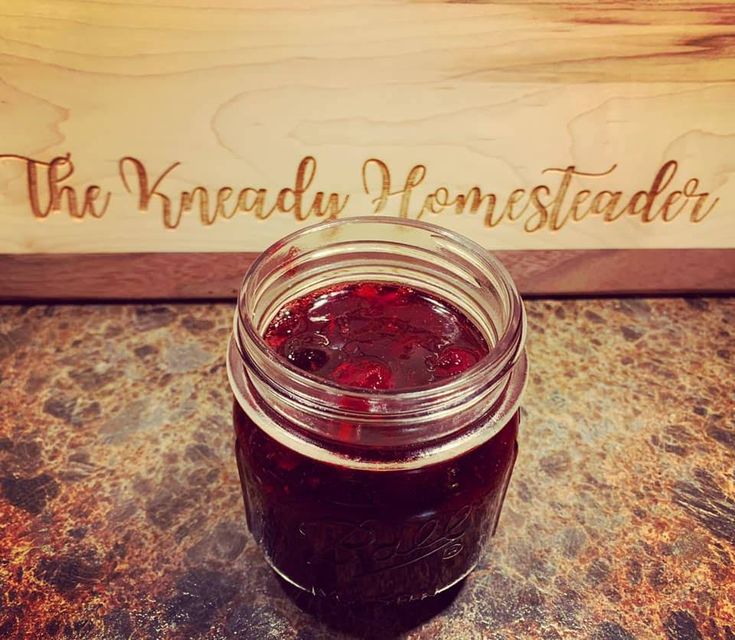 a jar filled with jam sitting on top of a table next to a wooden sign