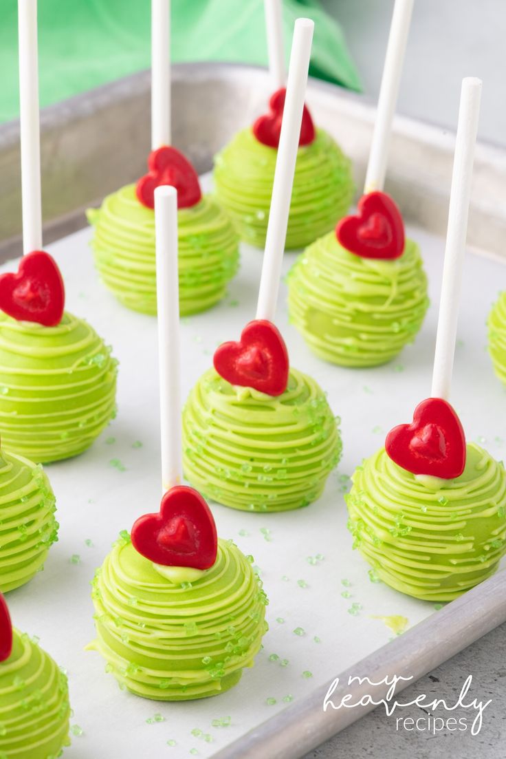 green cupcakes with red hearts on top and white sticks sticking out of them