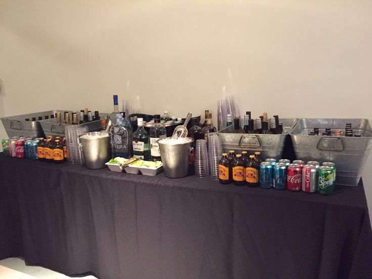 a table topped with lots of bottles and cans next to a black cloth covered wall